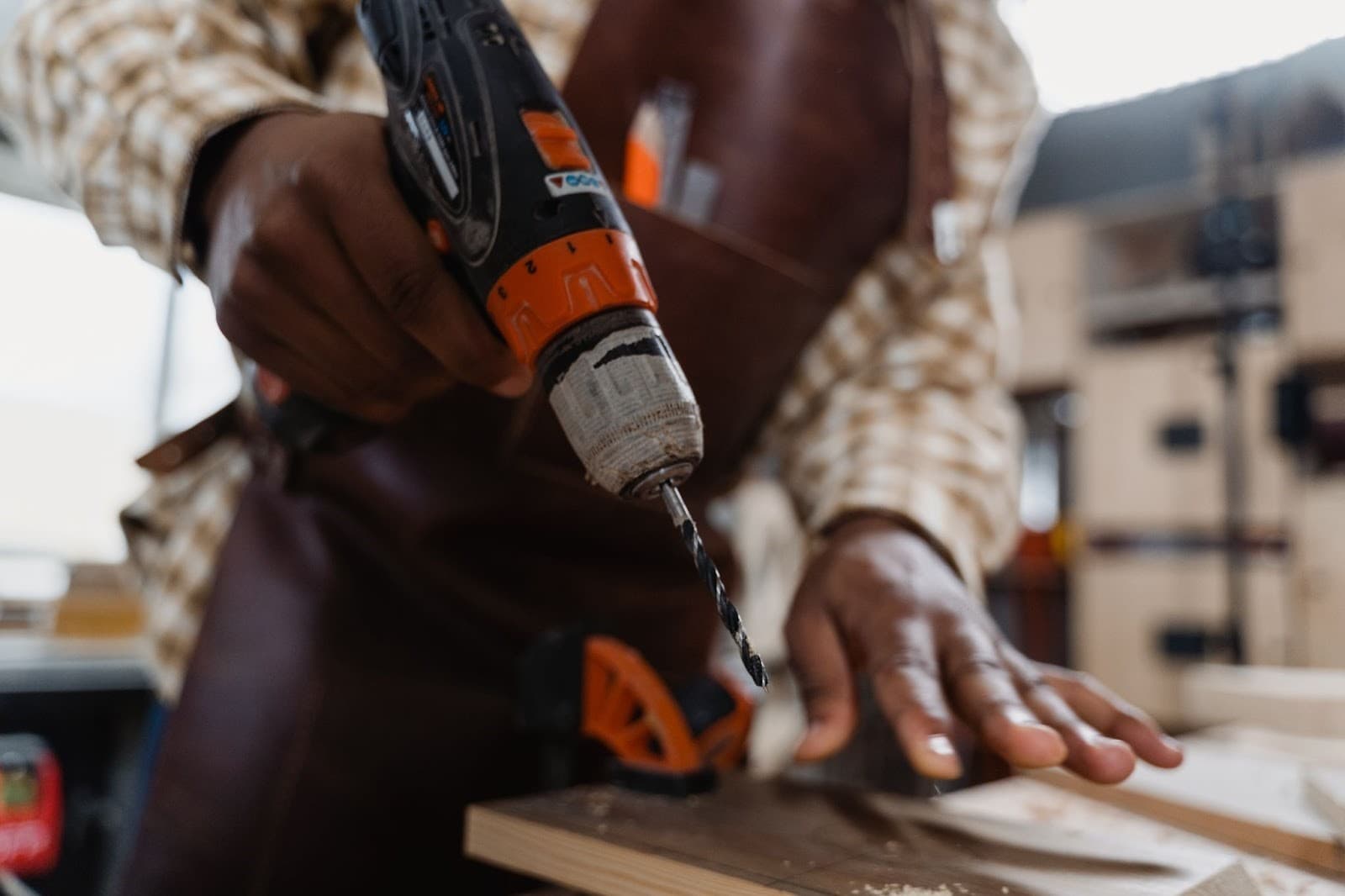 A man holding an electric drill at a workshop