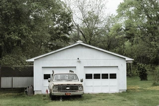 A white Chevy pickup truck parked in front of an outdoor shed